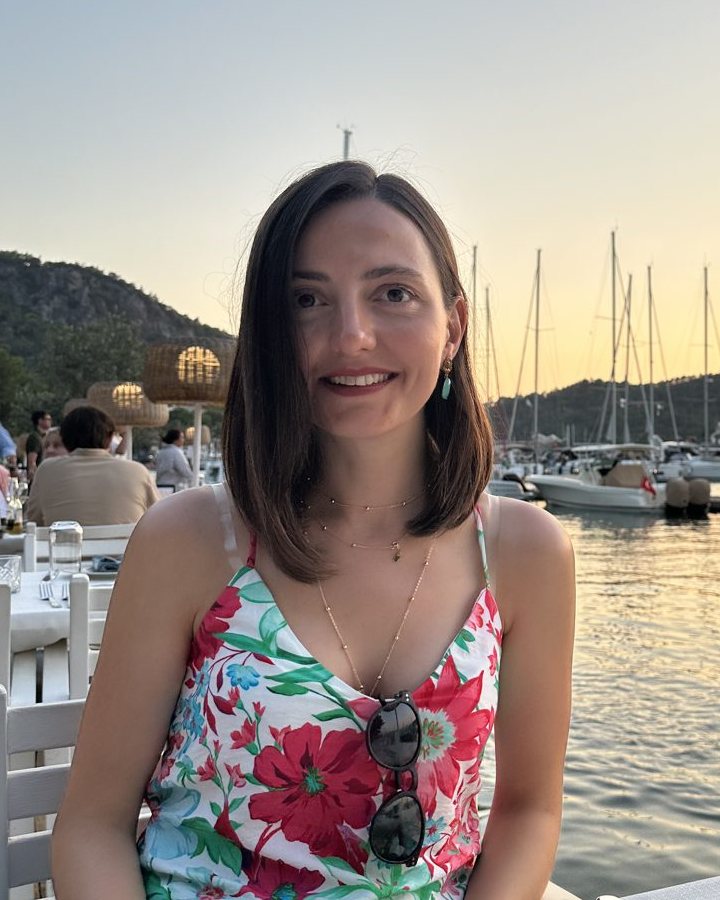 Özge Kafaonal gülümserken, gün batımında marinada